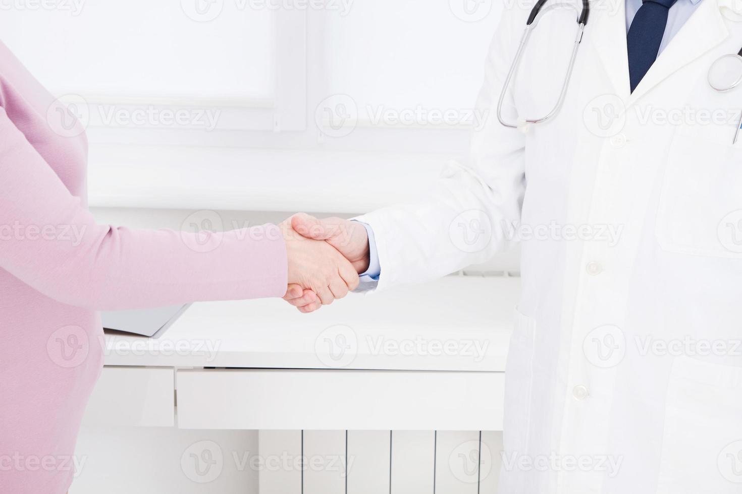 female hand of the doctor shakes the female arm of his patient in clinic, medical office. Healthcare concept, health insurance photo