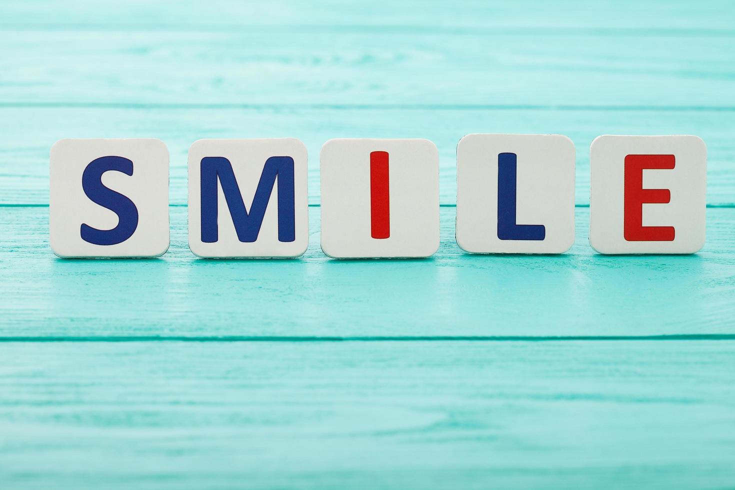 Word smile on blue wooden background. Selective focus. Copy space. Motivation concept photo