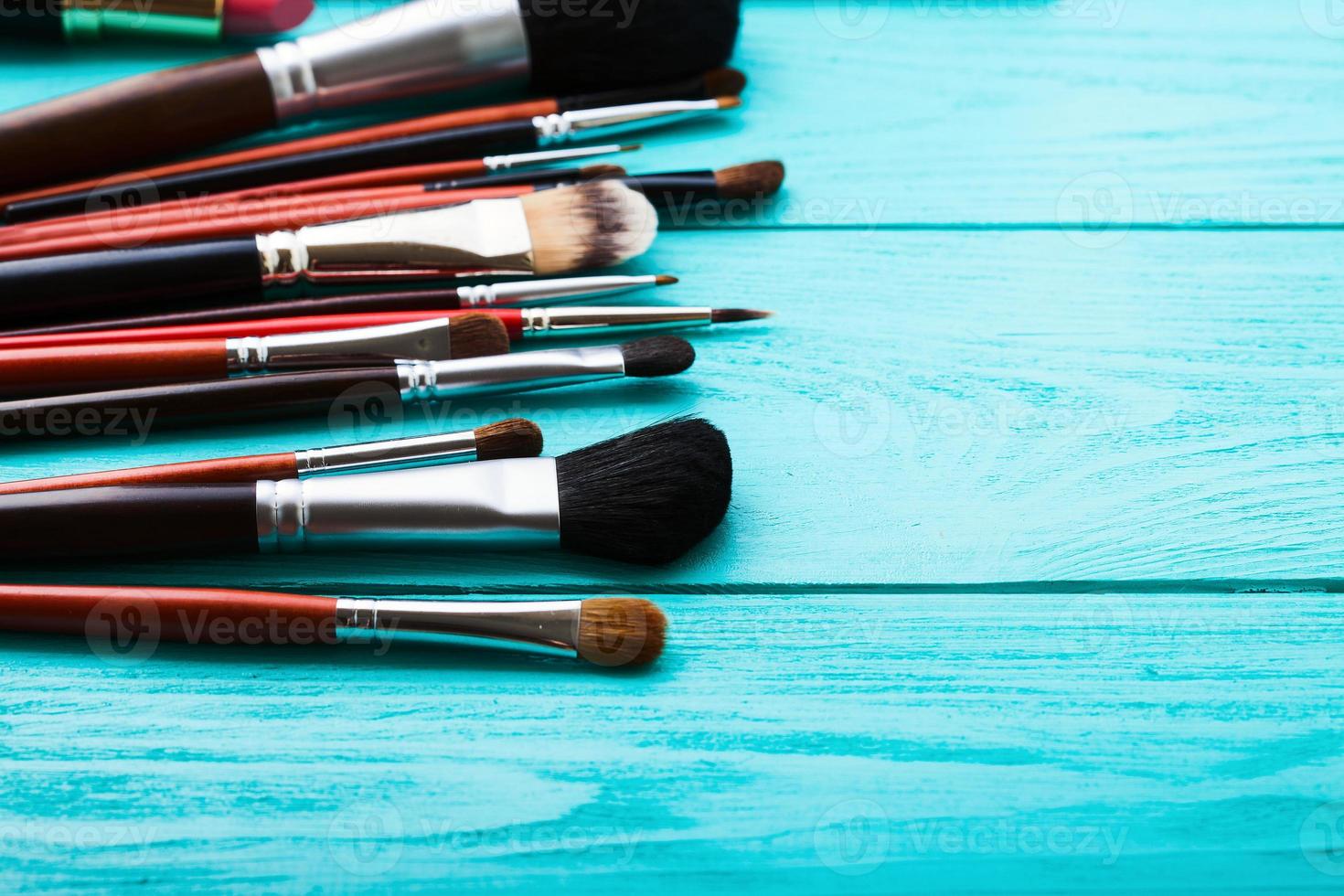 Make-up tools. Make up products. Lipstick, eye shadow, brushes.Cosmetics on blue wooden background.Selective focus photo