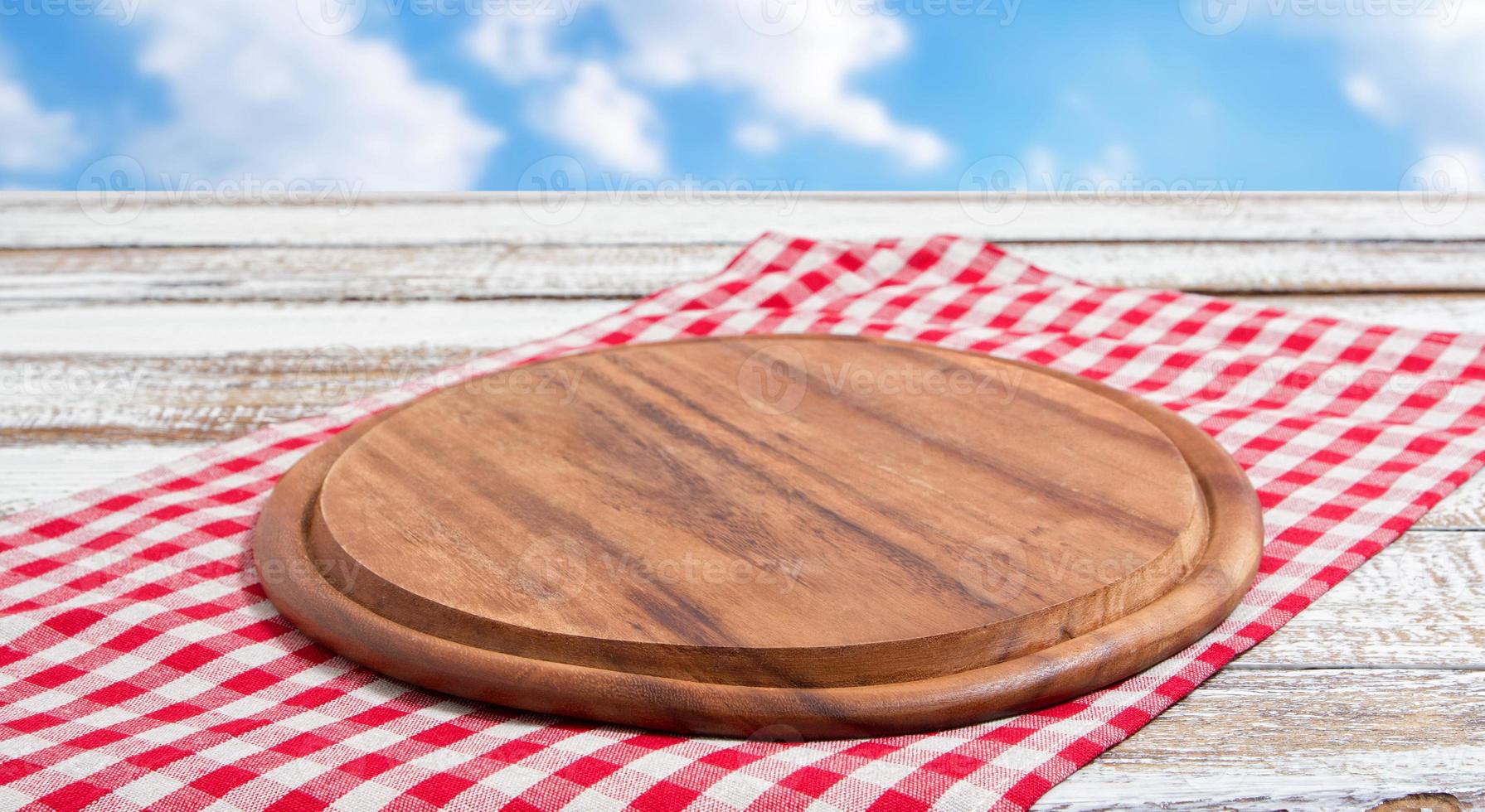 empty pizza board on empty wooden table with tablecloth,napkin - top view photo