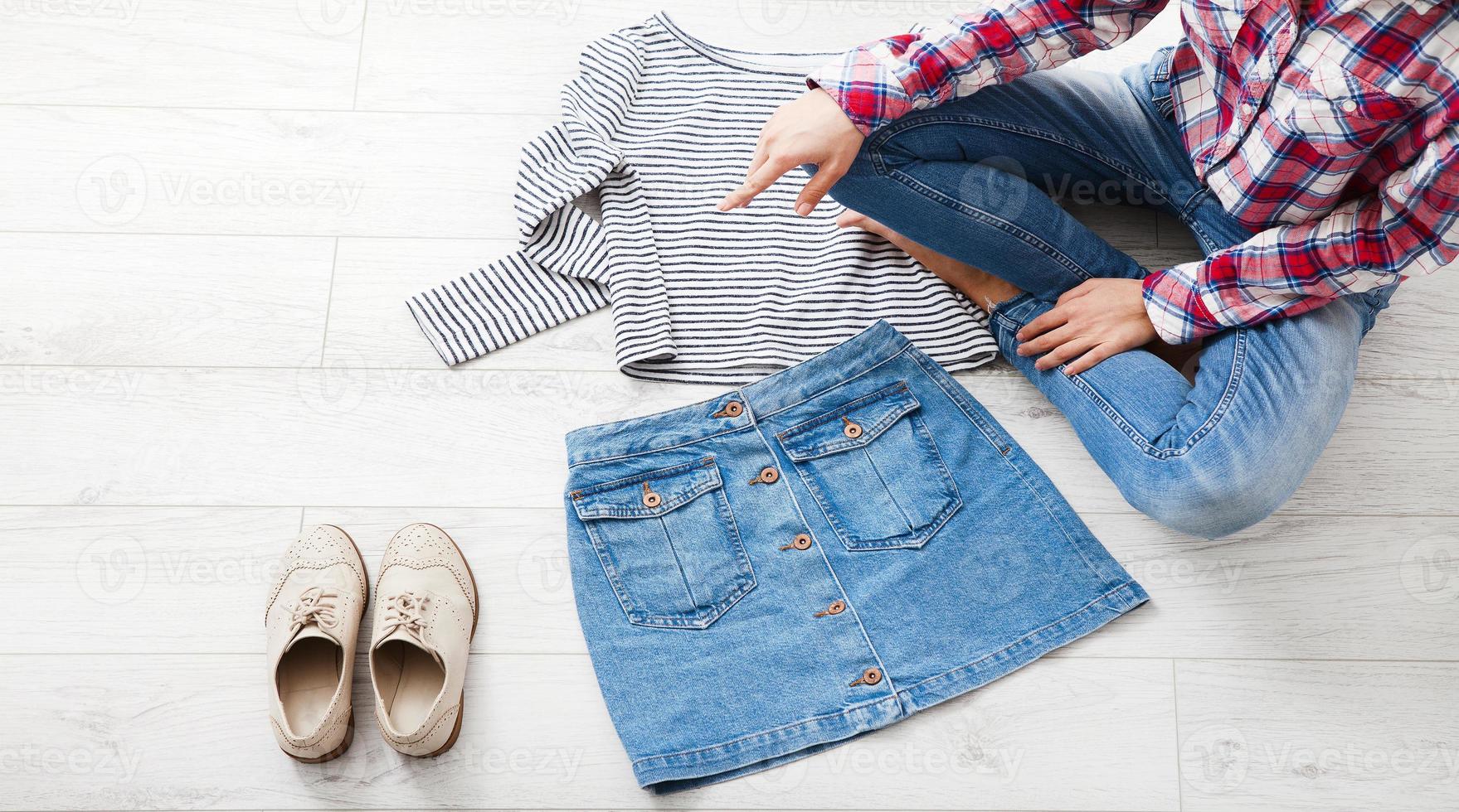 Casual summer outfit with different accessories and female legs in jeans on white wooden floor. Top view and copy space. photo