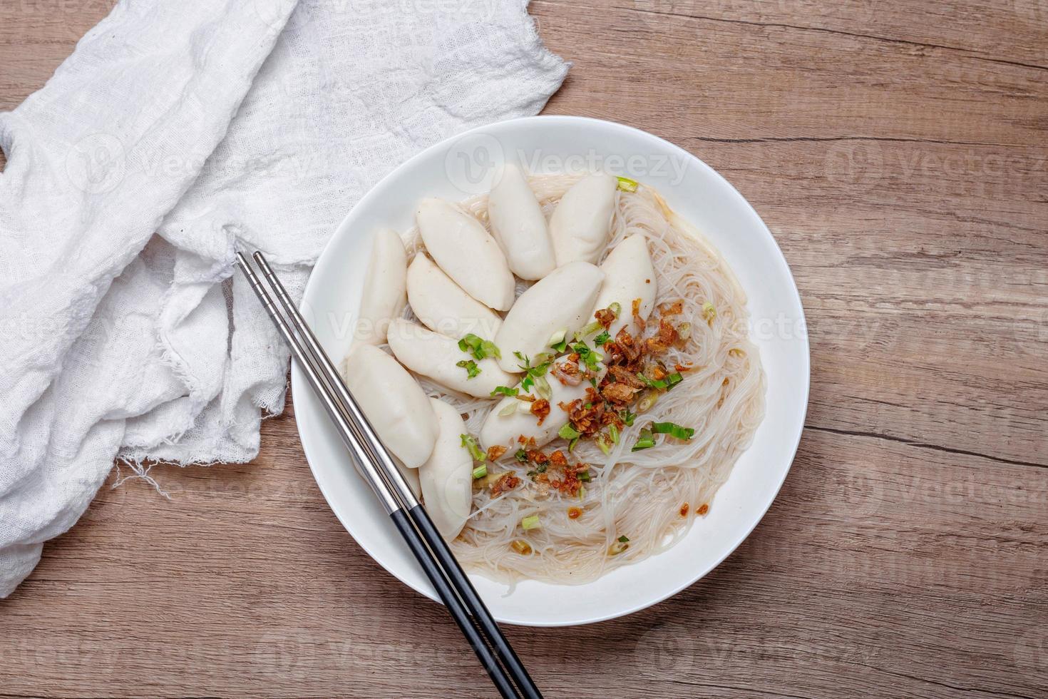 Fish ball noodles in clear broth on wooden floor photo