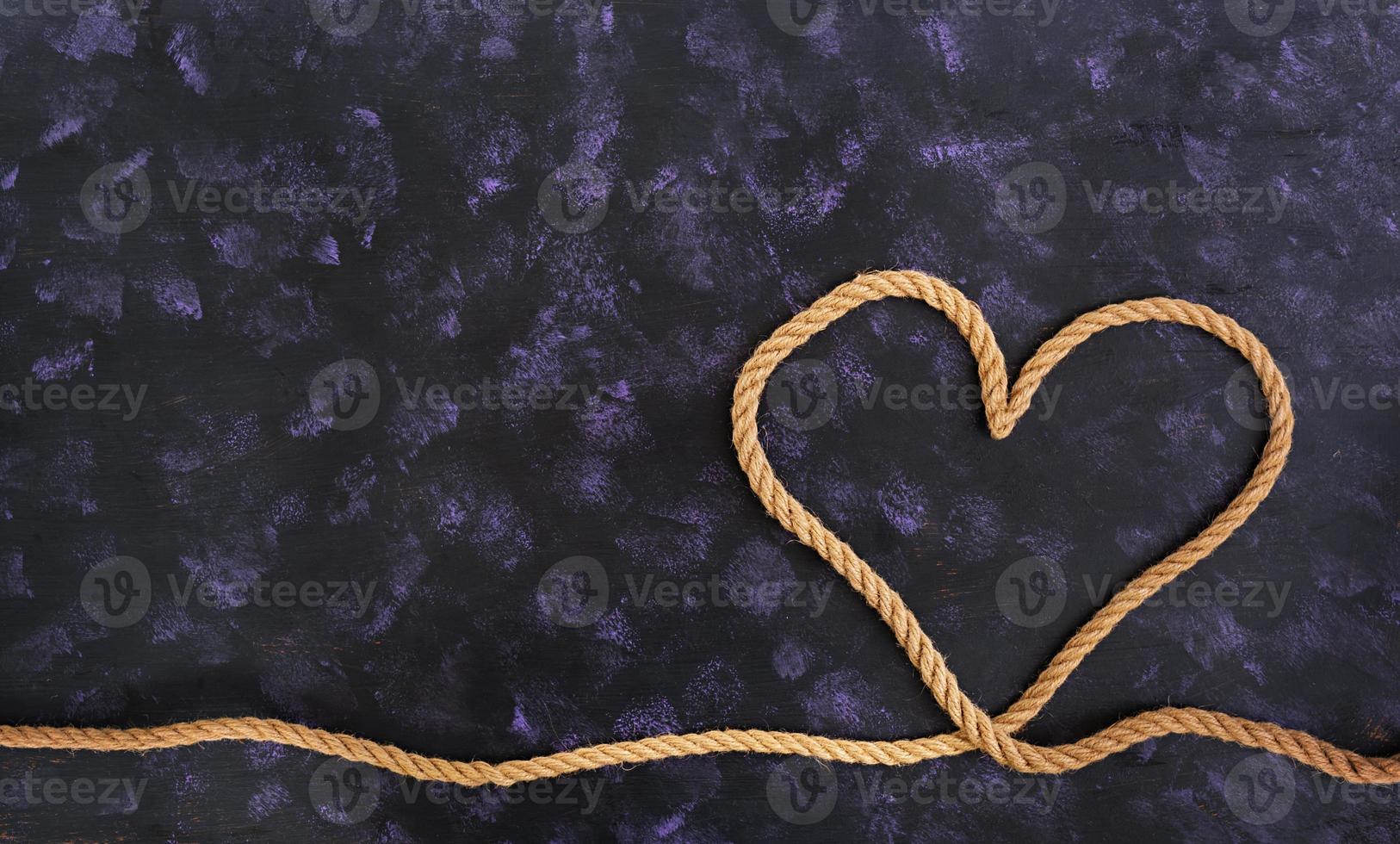 Heart shape made with rope on dark background photo