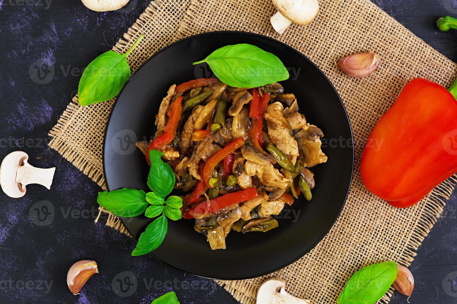 Stir Fry Chicken with peppers and peas on dark background. Top view photo