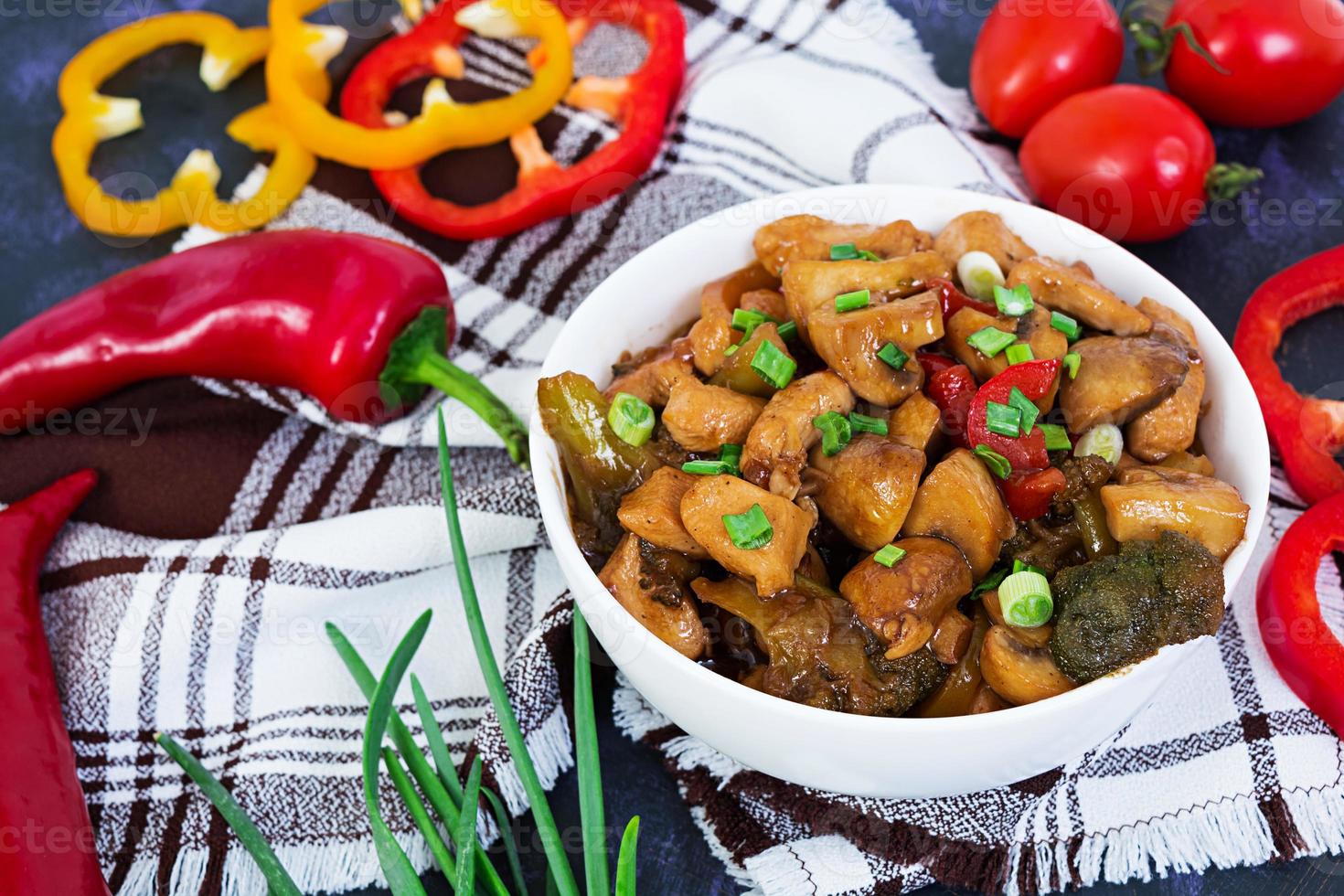 saltee el pollo con pimientos y champiñones sobre fondo oscuro foto