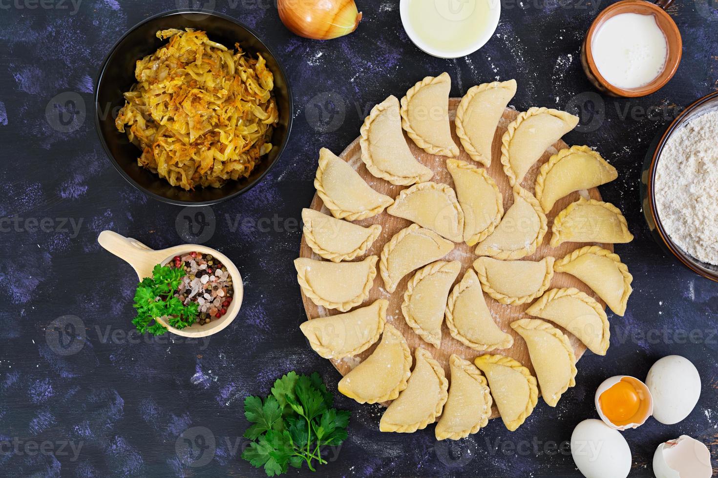 Delicious dumplings with cabbage on dark background. Top view photo