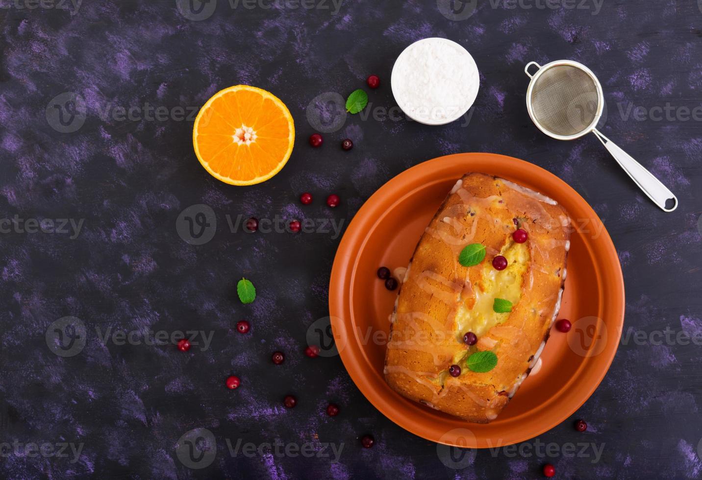 Cupcake with orange and cranberries on dark purple background. Top view photo