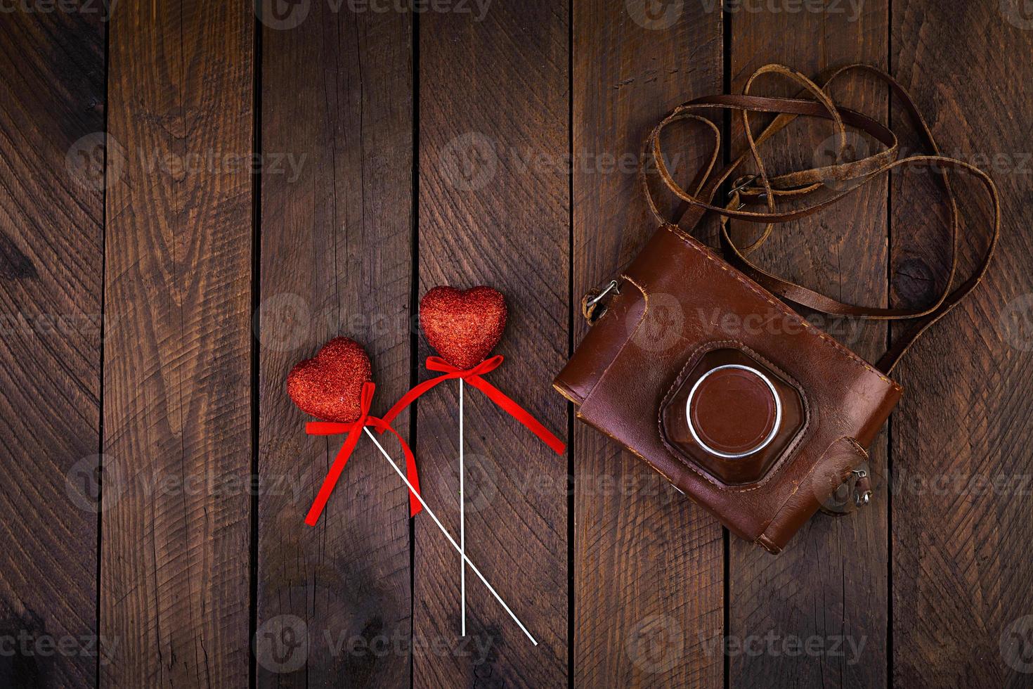 Vintage old camera with hearts on rustic wooden background. Top view photo