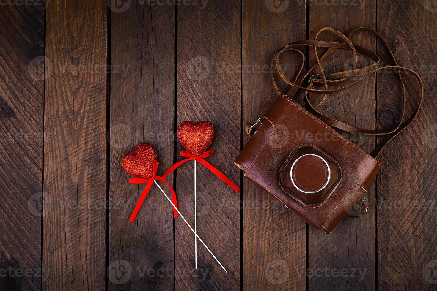 Vintage old camera with hearts on rustic wooden background. Top view photo