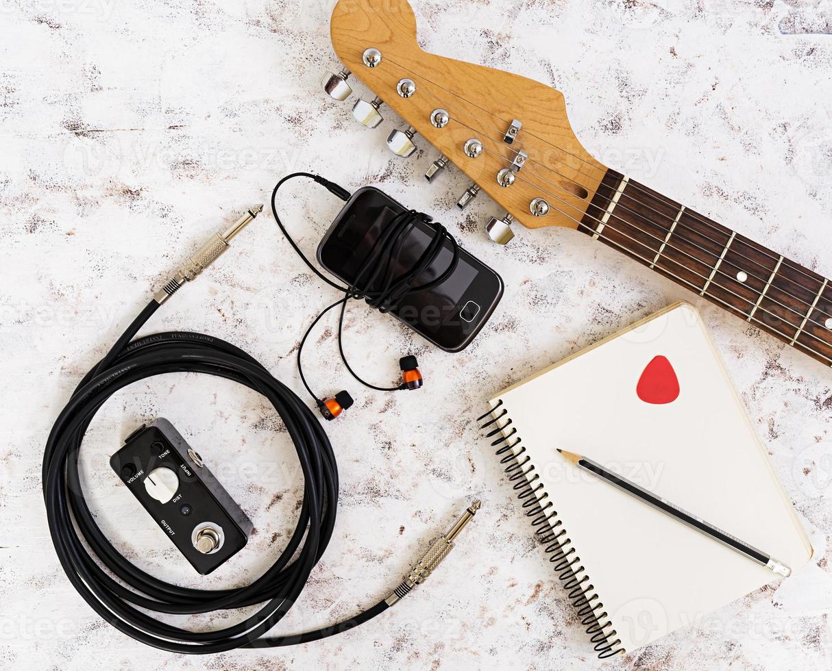 cosas de musica guitarra, pedal de guitarra, auriculares, teléfono móvil sobre fondo blanco. vista superior. endecha plana foto