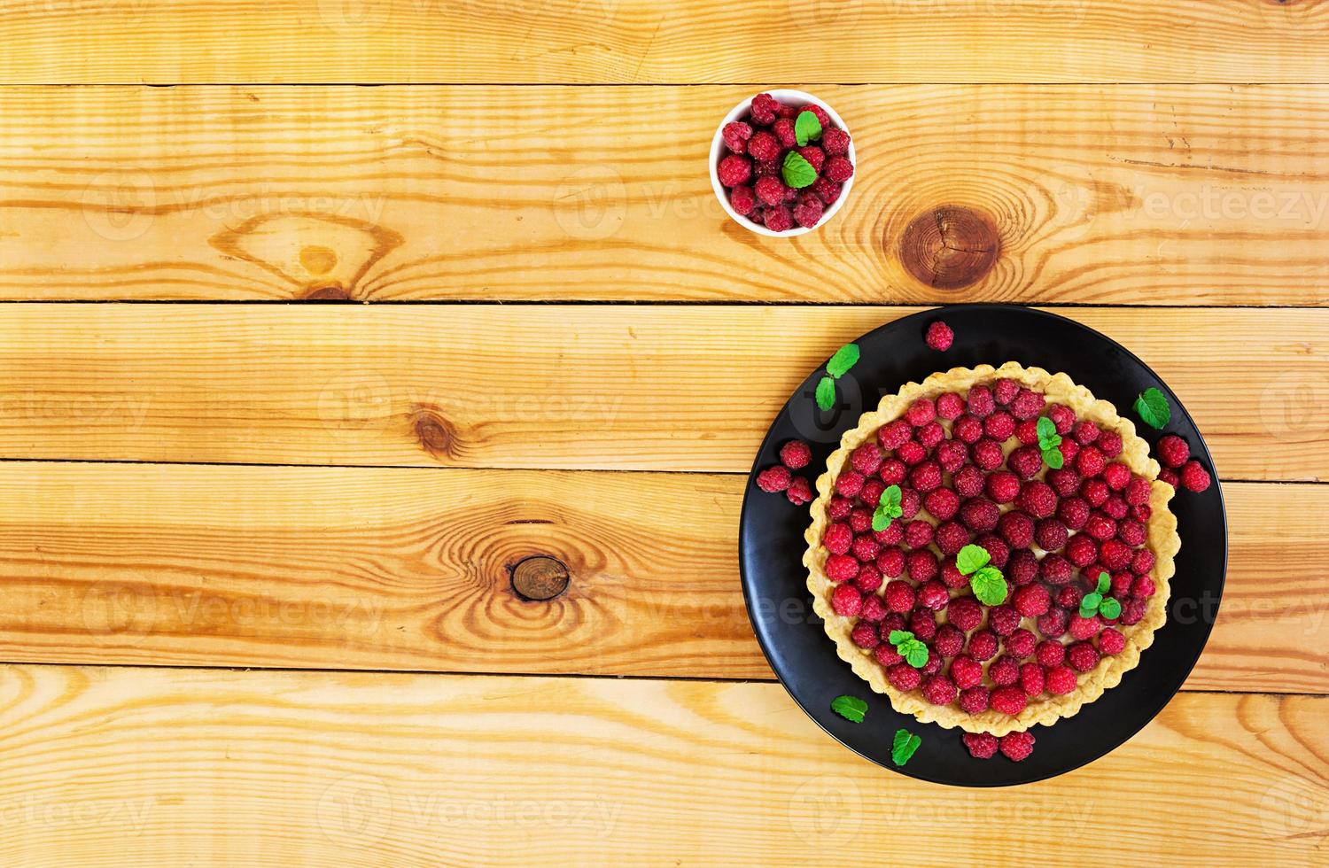 Delicious tart with custard and raspberry on wooden background photo