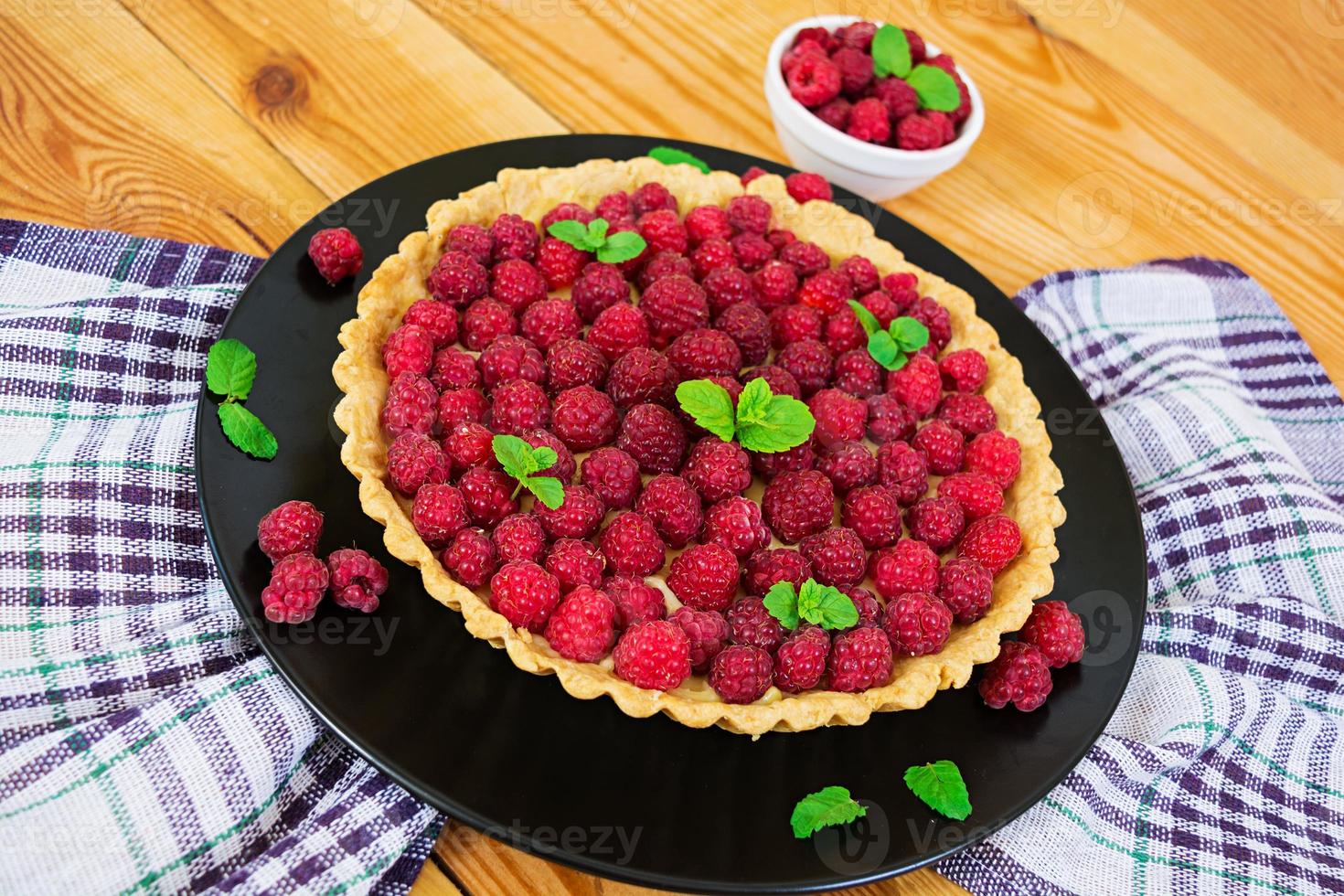 Delicious tart with custard and raspberry on wooden background photo