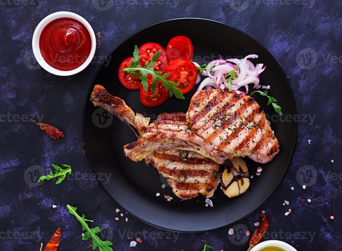 Raw pork steak with herbs on dark background. Raw juicy steak on bone. Top view photo