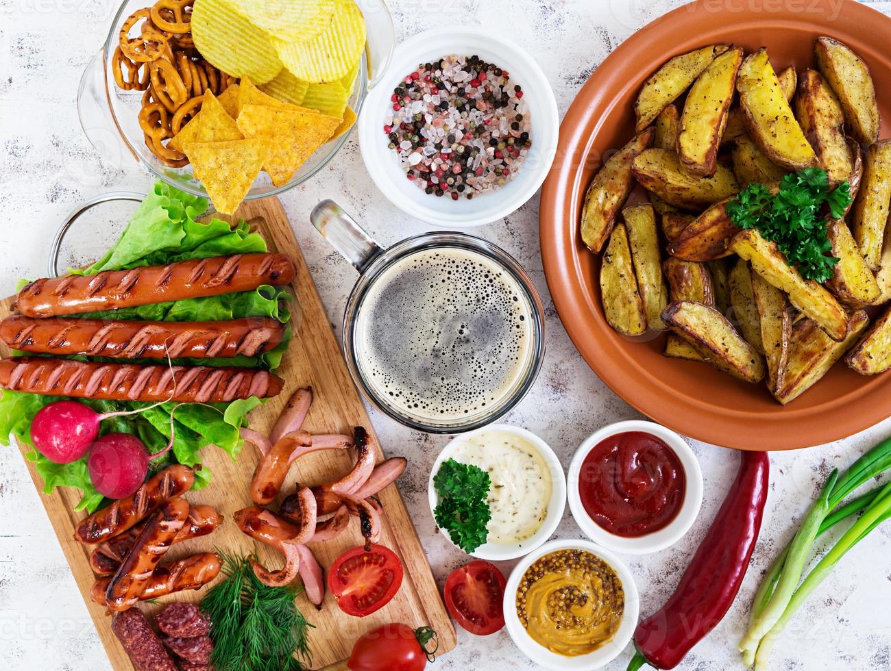 Baked potato wedges with sausages and spices. Top view photo