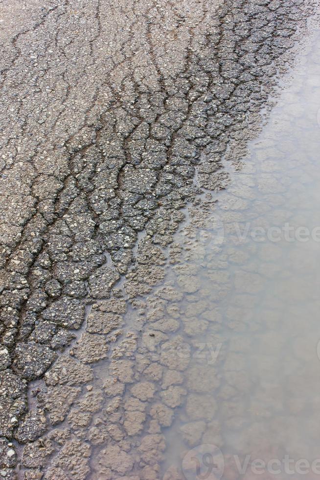 asfalto agrietado de fondo con agua. foto