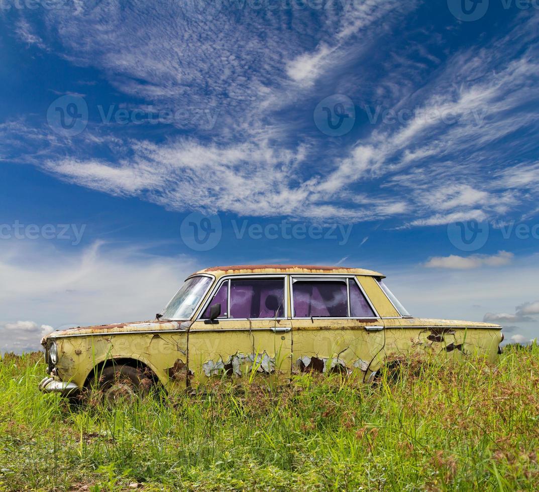 Old model sedan in grass sky clouds. photo