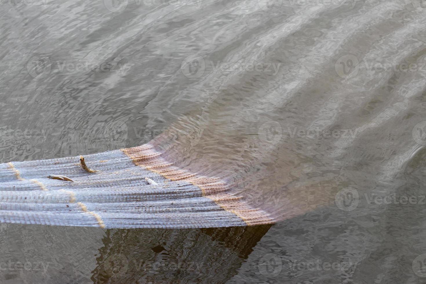 Fishing net is pulled from the water. photo