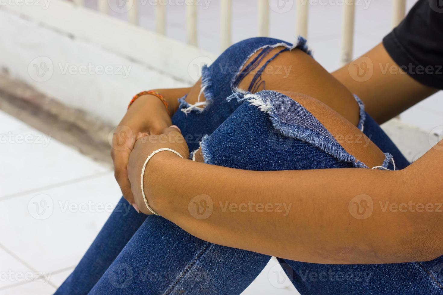 Female hugging knee torn jeans. photo