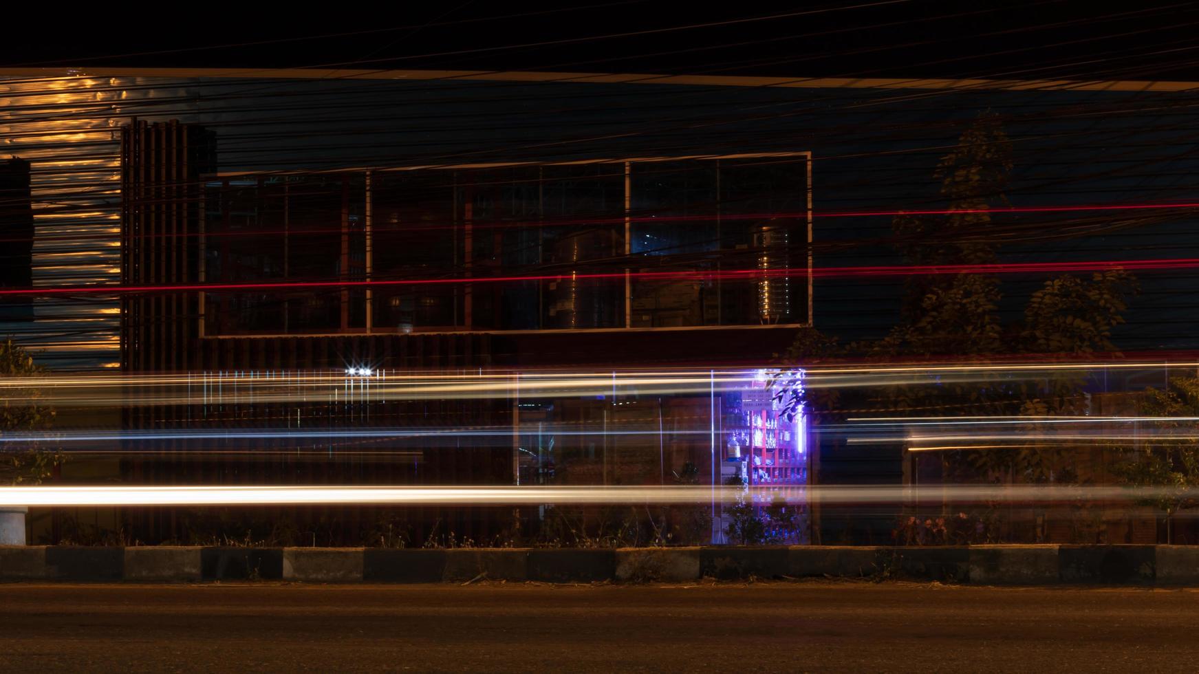 líneas de luz de los faros de los coches cerca de los edificios nocturnos. foto