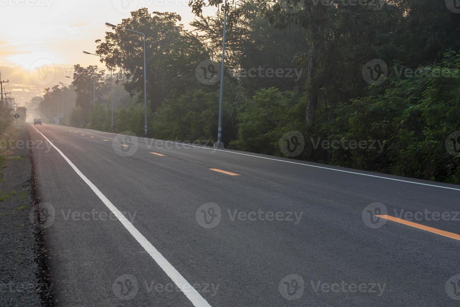 carretera asfaltada con sol naciente en el campo. foto