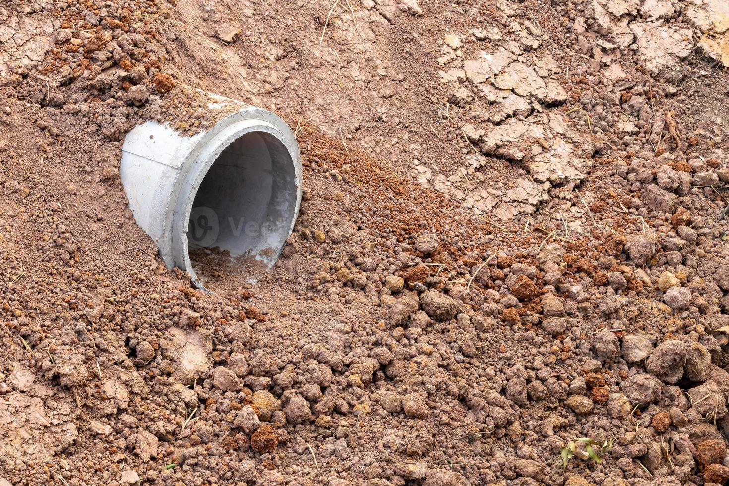 Small concrete pipe buried in sandy soil. photo