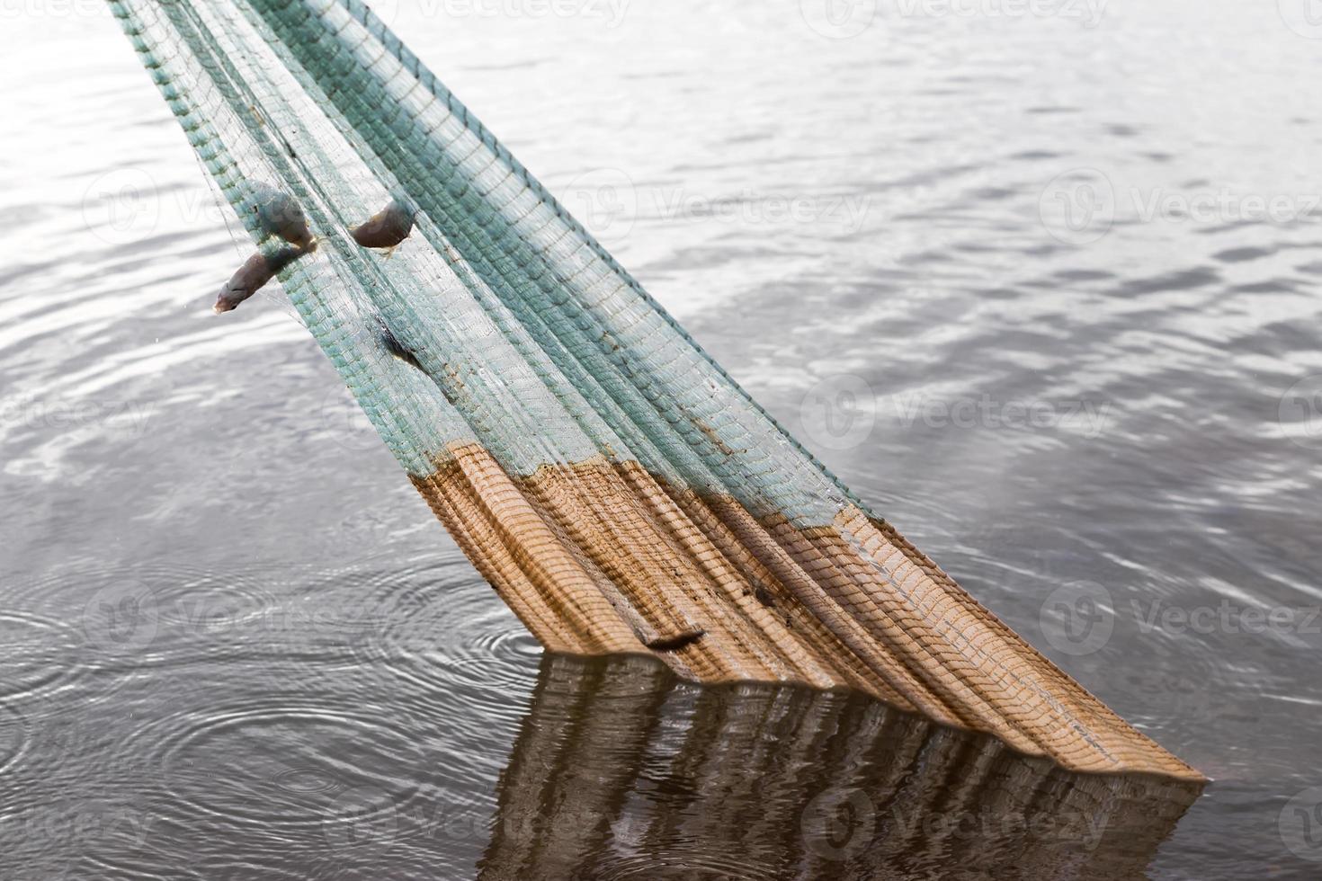 Fishing net is pulled from the water. photo