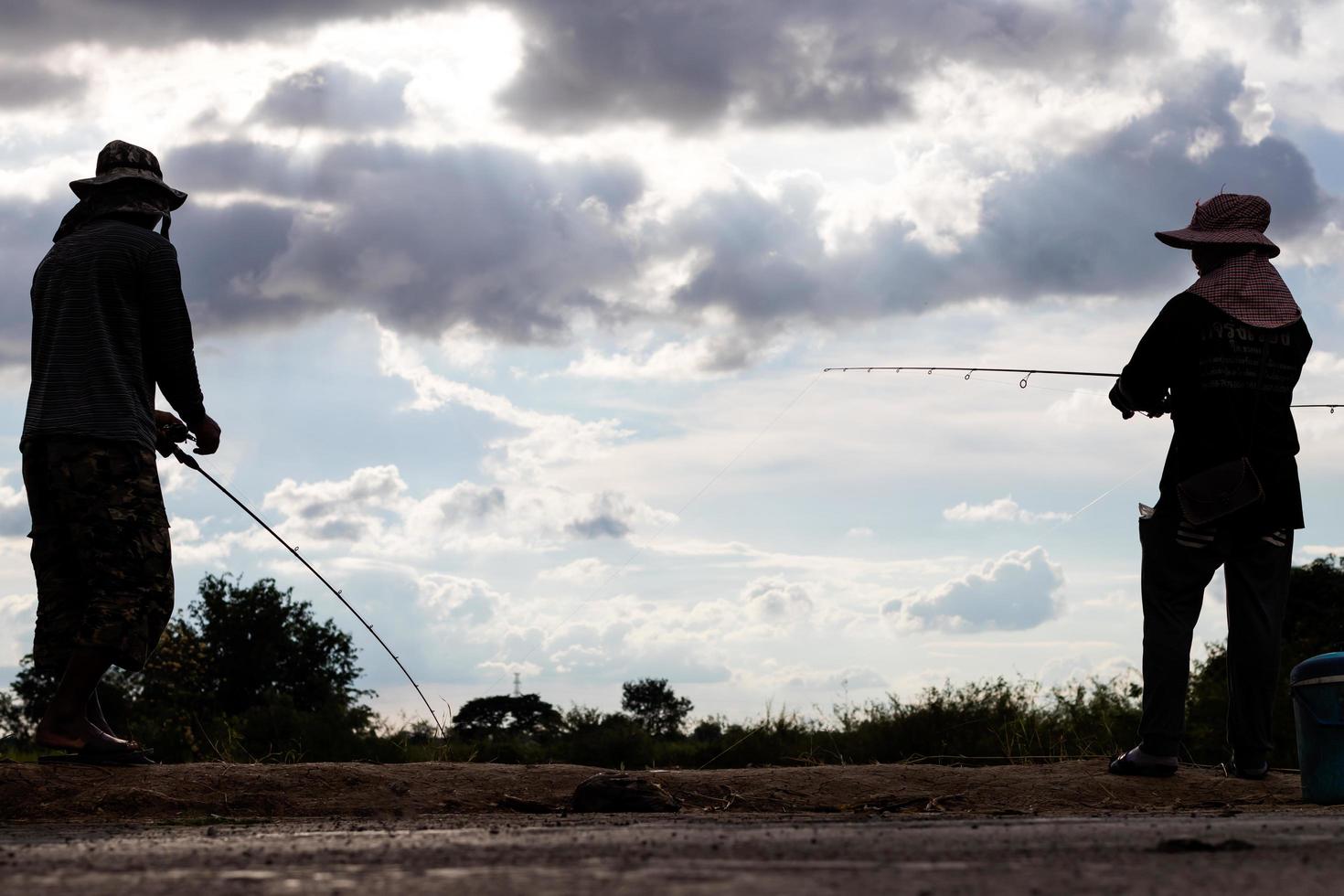 Silhouette men and women stand fishing. photo