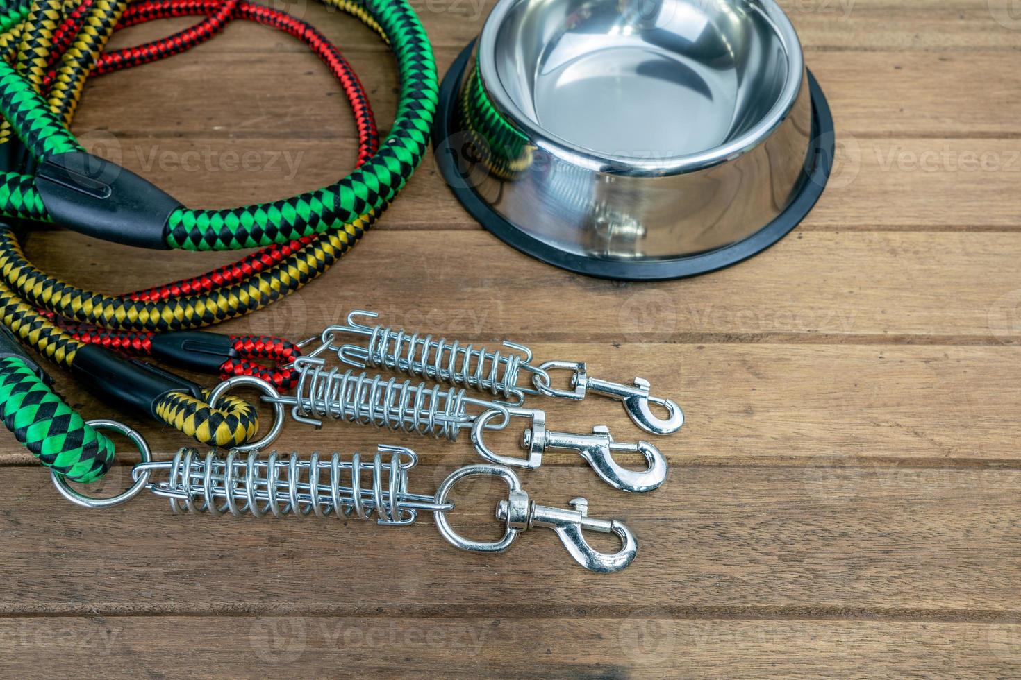 Pet leashes with hook and stainless bowl on wooden table.  Pet accessories concept photo