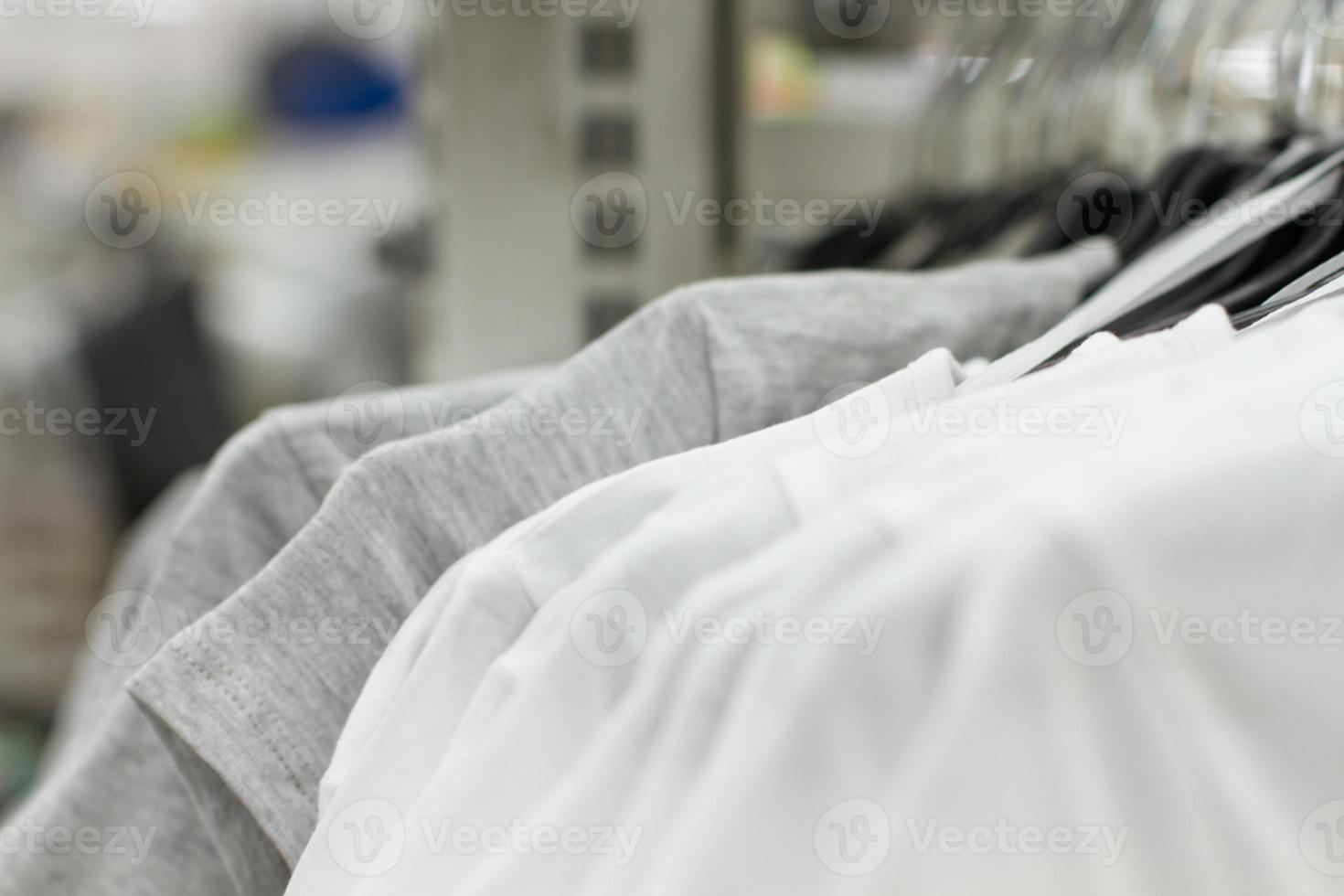 Some used clothes hanging on a rack in a flea market. Background of dress. Selective focus. photo