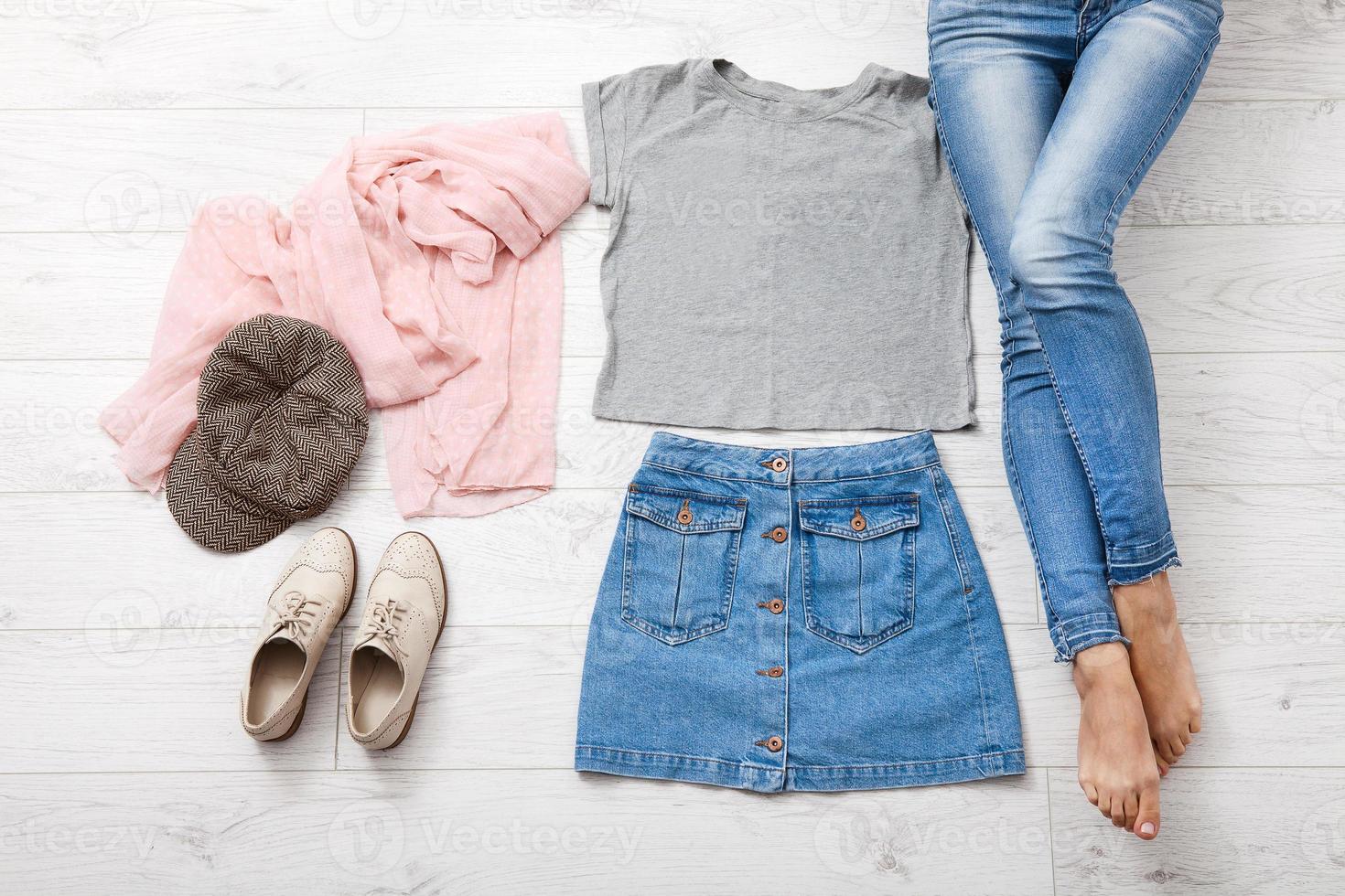 Casual summer outfit with different accessories and female legs in jeans on white wooden floor. Top view and copy space. photo