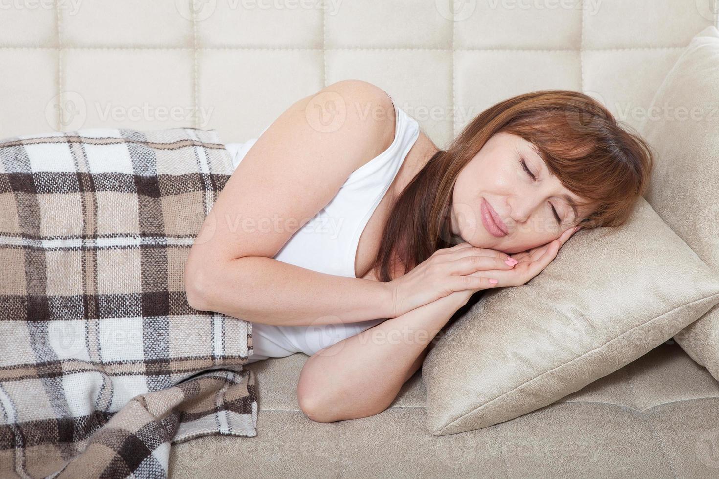 Daytime sleep. Middle age woman sleeping on bed in modern apartment. Home background. Copy space and mock up. Menopause photo