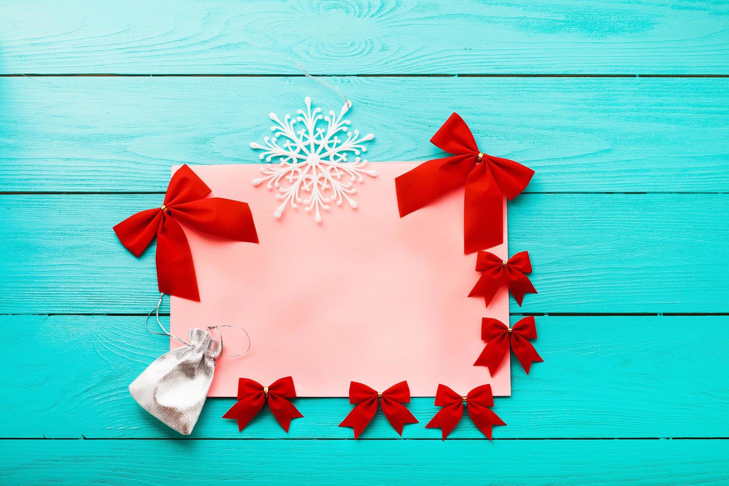 Frame of red bows with winter accessories on blue wooden background. Top view photo