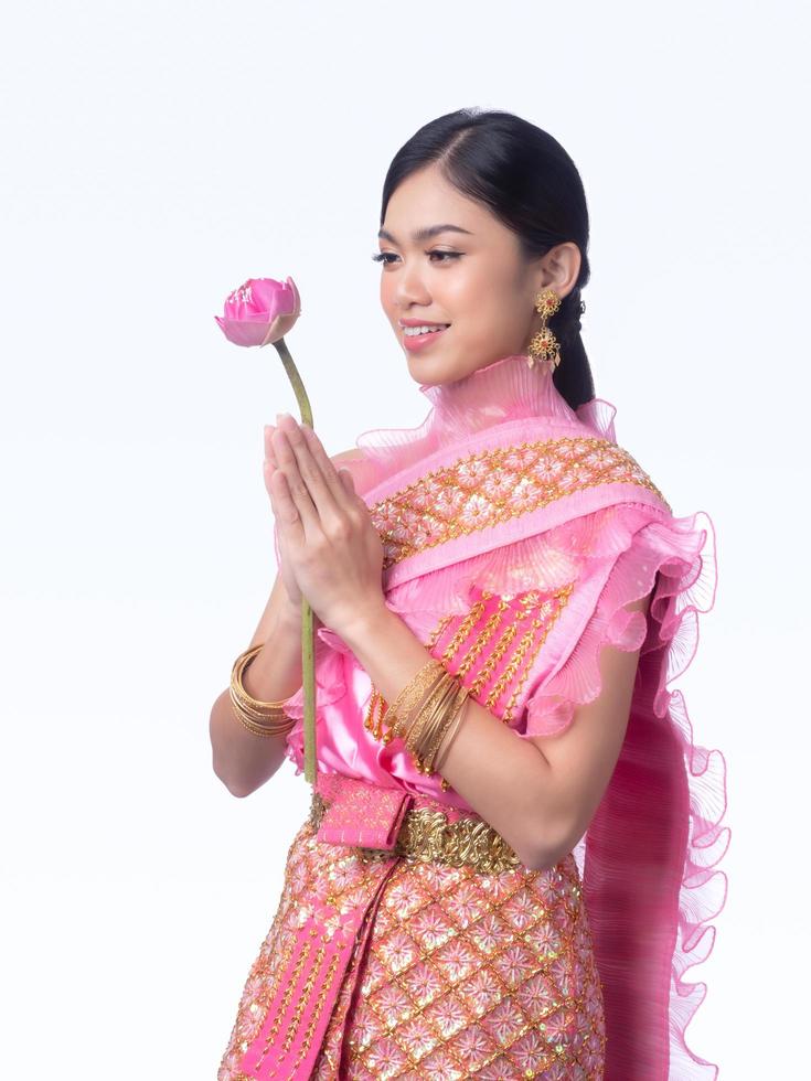 una encantadora mujer tailandesa con un antiguo vestido tailandés sosteniendo una flor de loto que se usa para adorar a los monjes religiosos foto