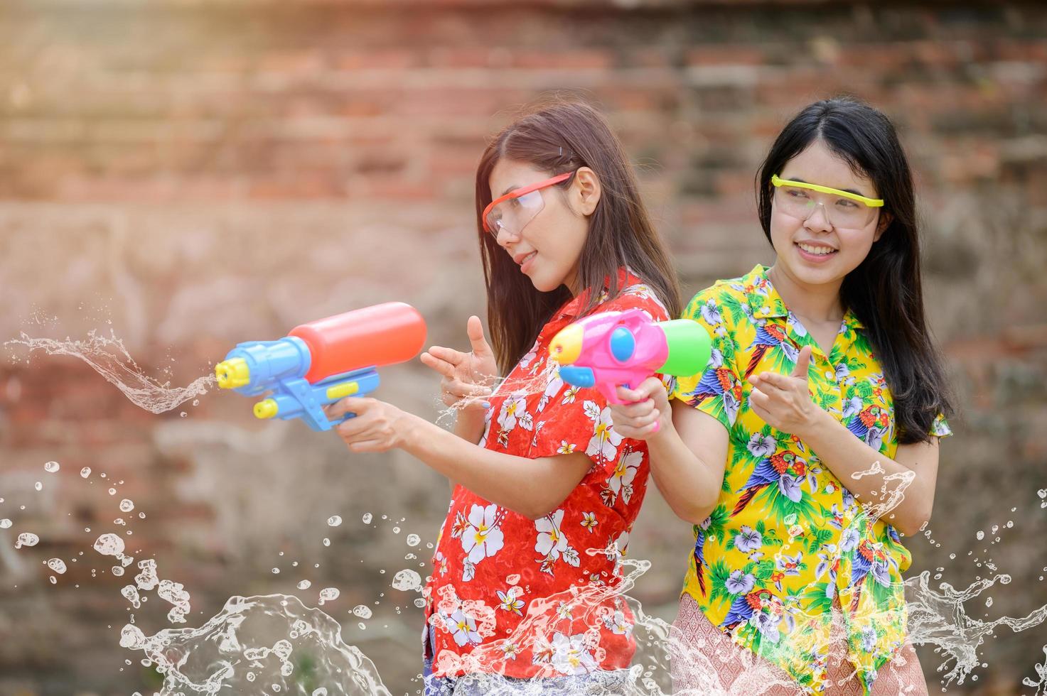 Beautiful Asian women hold plastic water guns at an ancient temple during Songkran, the most beautiful and fun water festival in Thailand photo