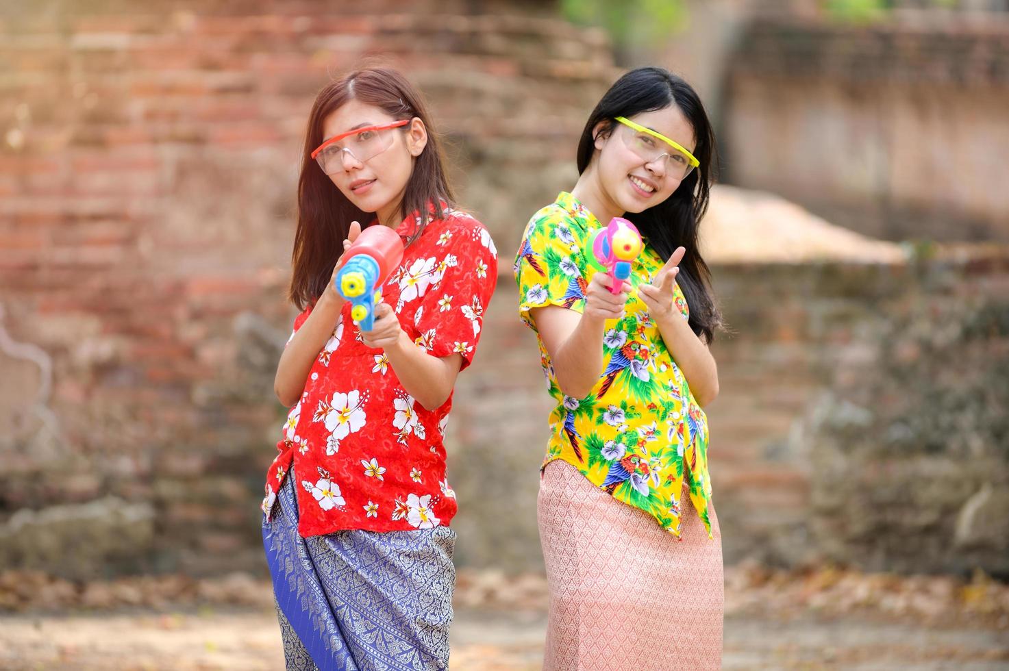 Beautiful Asian women hold plastic water guns at an ancient temple during Songkran, the most beautiful and fun water festival in Thailand photo