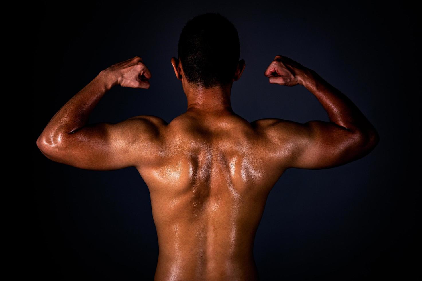 un hombre asiático fuerte levantó los brazos para mostrar sus músculos fuertes y hermosos del ejercicio foto