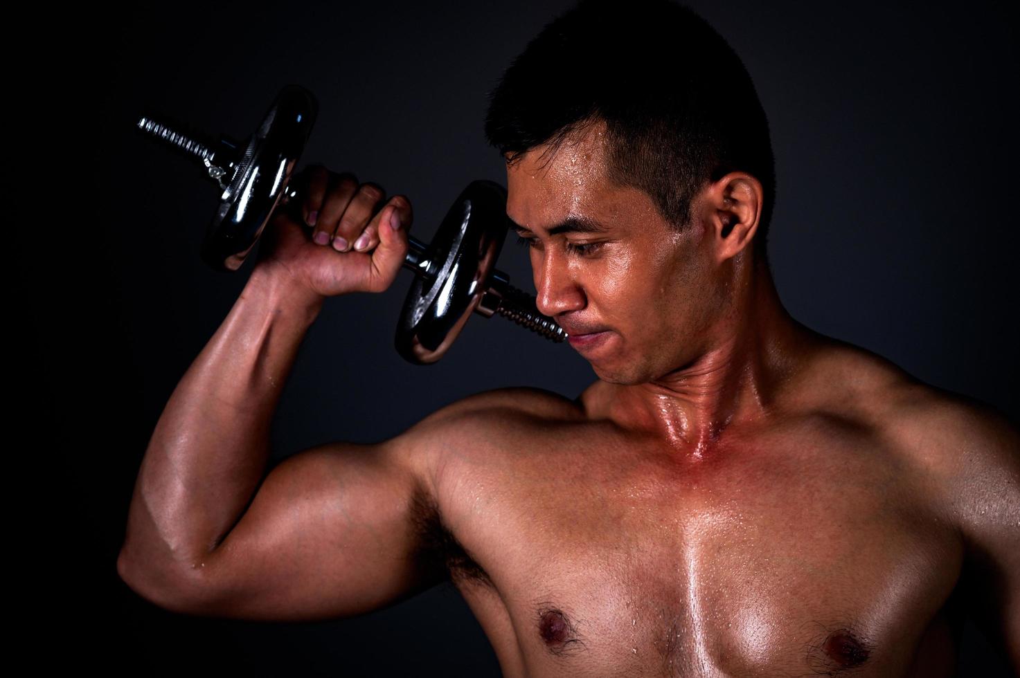The strong Asian man lifted his dumbbell regularly to keep his muscles strong and beautiful photo