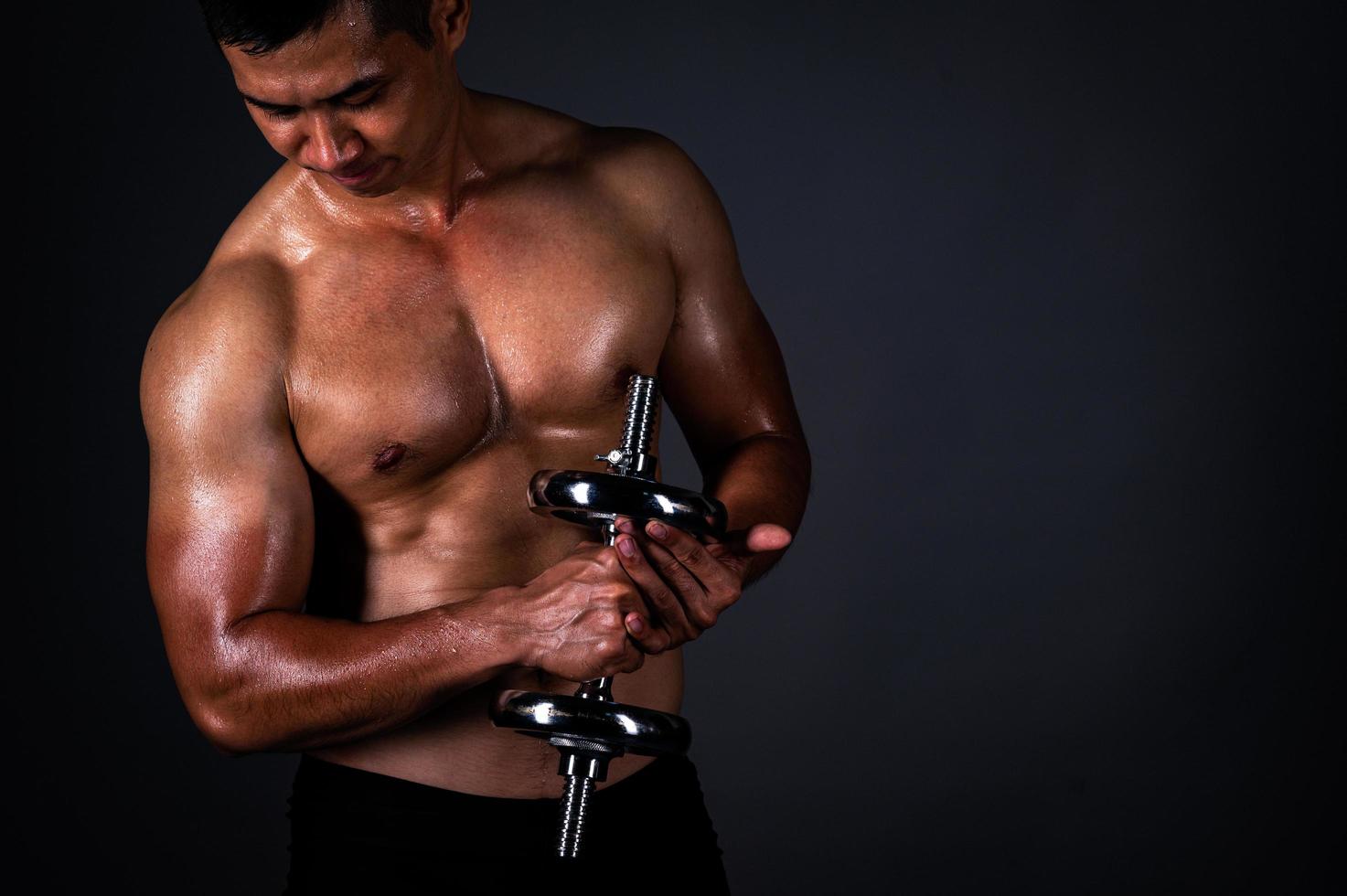 The strong Asian man lifted his dumbbell regularly to keep his muscles strong and beautiful photo