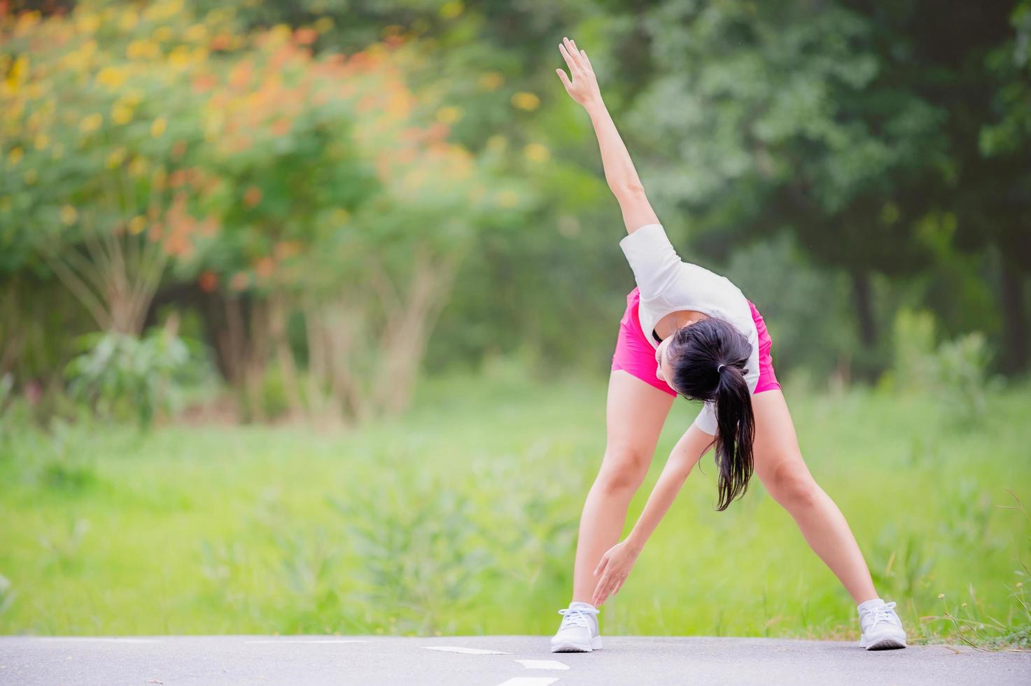 una hermosa mujer asiática se está calentando, para flexibilizar los músculos antes de ir a correr foto