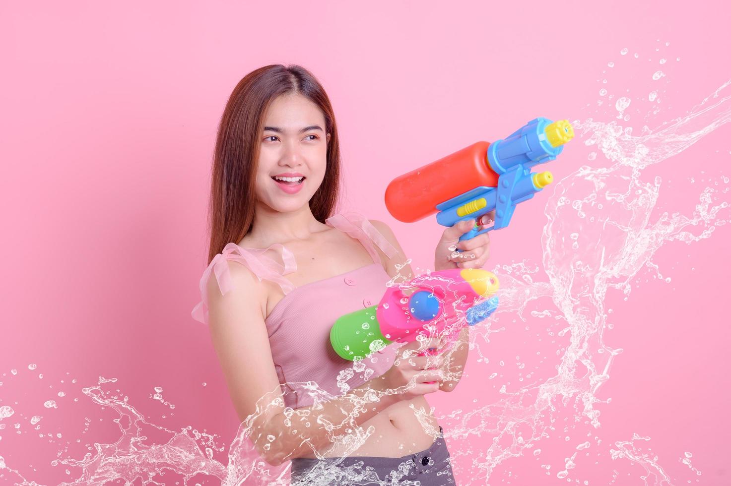 A beautiful Asian woman shows a gesture while holding a plastic water gun during the Songkran festival photo