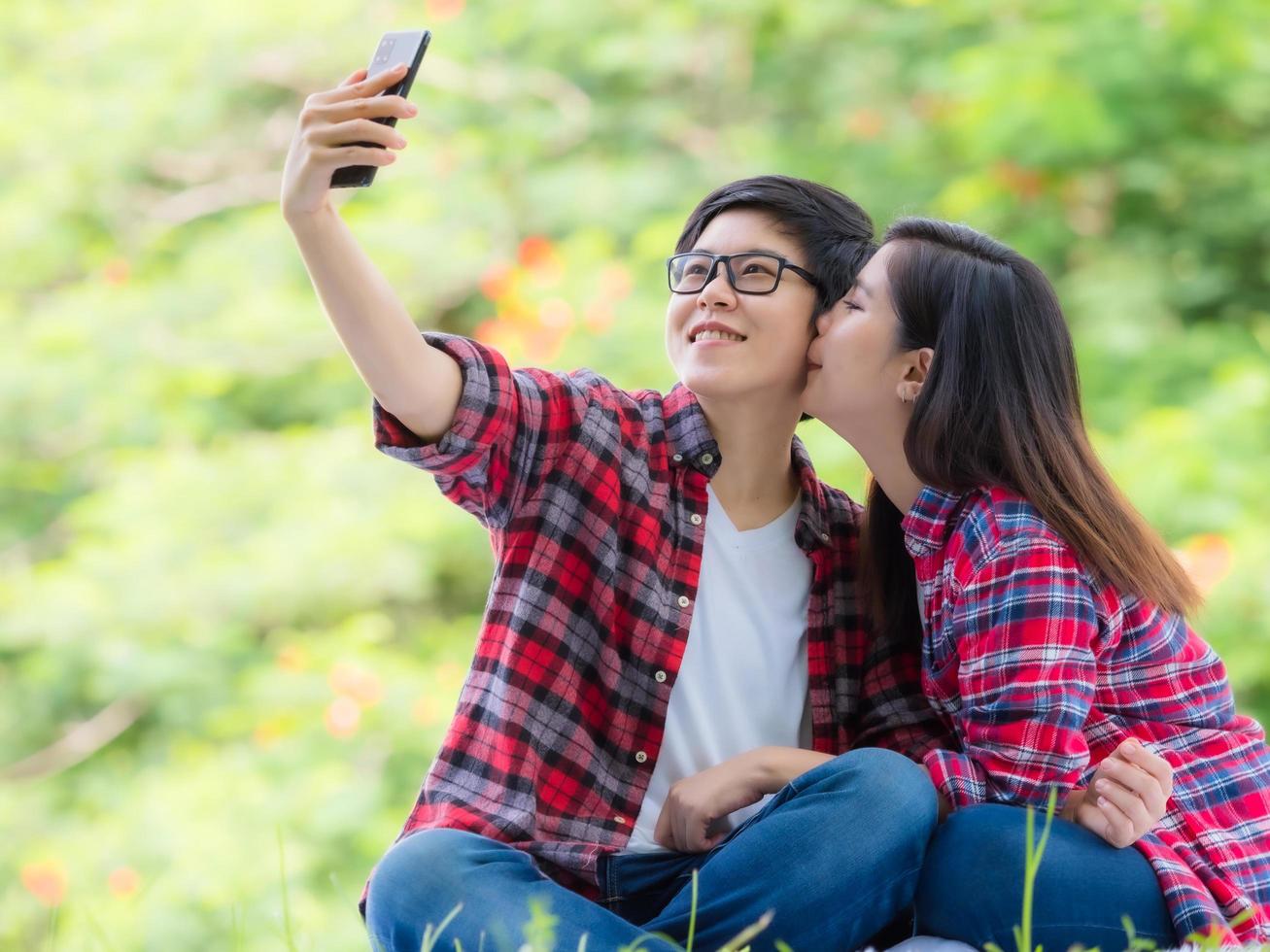 Asian female couples LGBT sitting and take a photo in the garden and embrace each other in love and happiness