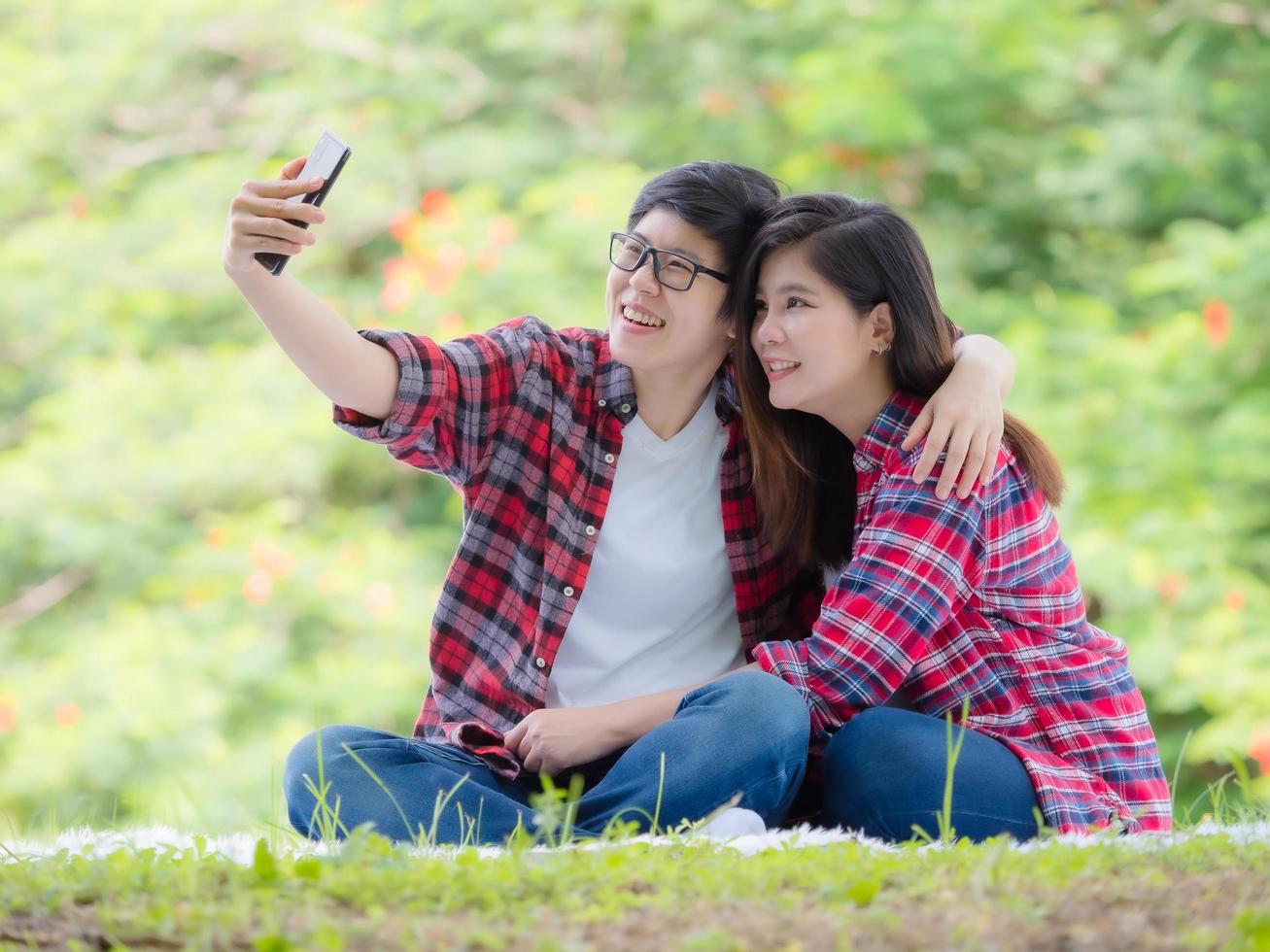 Asian female couples LGBT sitting and take a photo in the garden and embrace each other in love and happiness