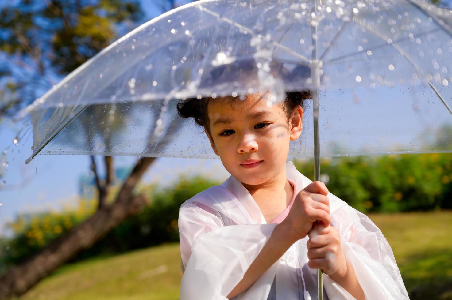 A little girl was happily standing in an umbrella against the rain photo