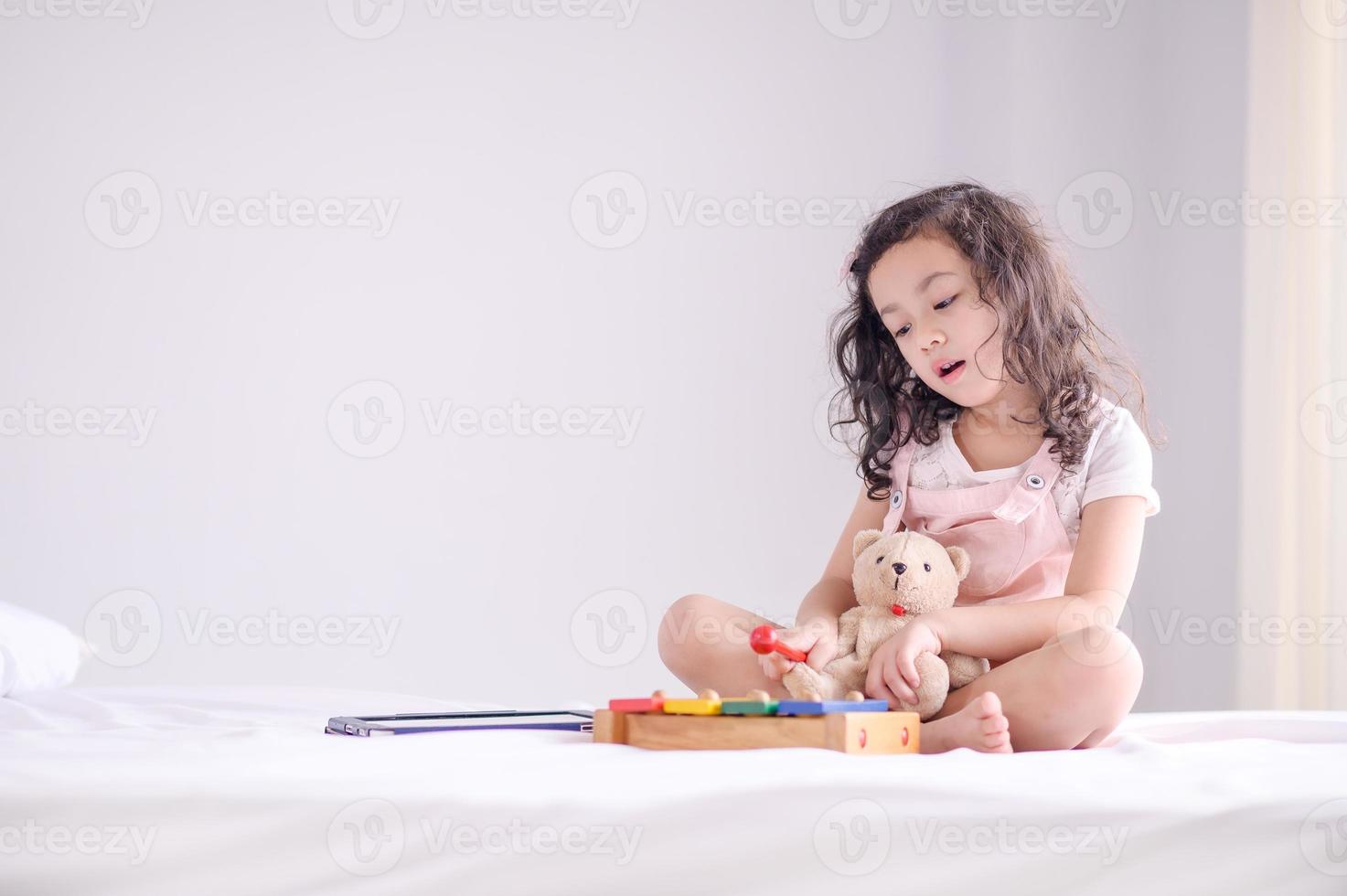 una linda joven asiática estaba felizmente tocando un instrumento de juguete de madera en el dormitorio foto