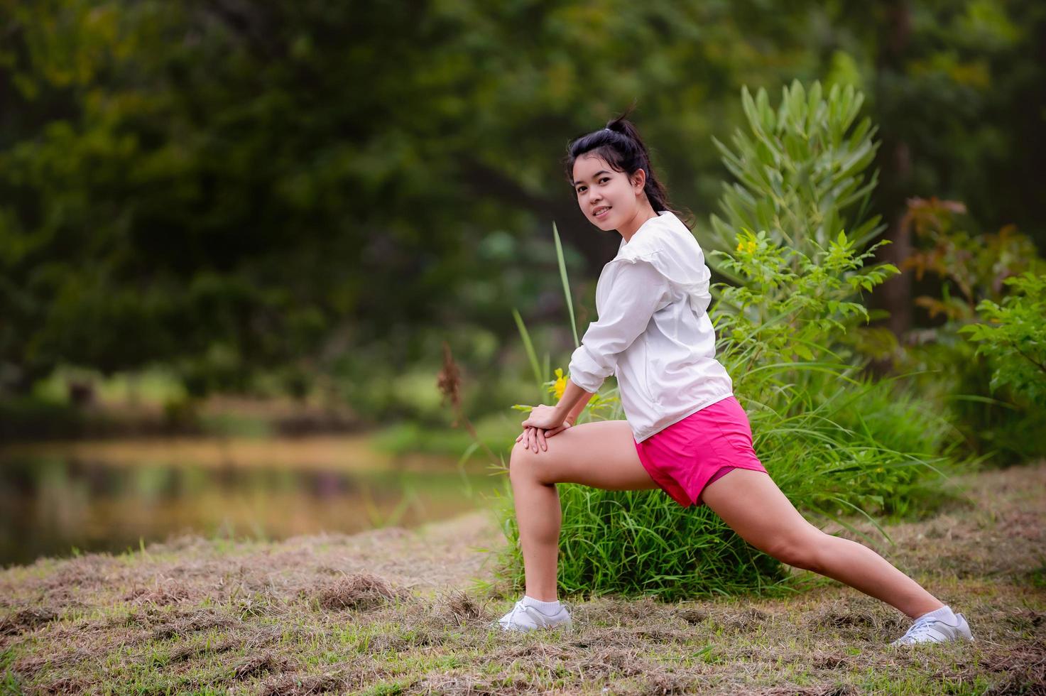 una hermosa mujer asiática se está calentando, para flexibilizar los músculos antes de ir a correr foto