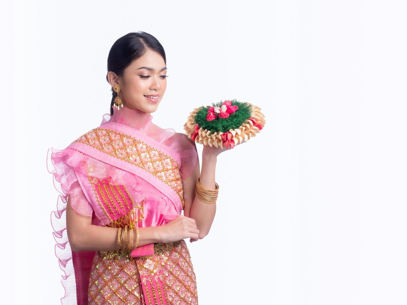 atractiva mujer tailandesa vestida con ropa tradicional tailandesa sostiene una canasta de flores foto