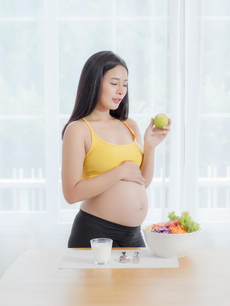 A beautiful pregnant woman in a Japanese room preparing a vegetable and fruits salad to eat for good health for the mother and baby in the womb photo