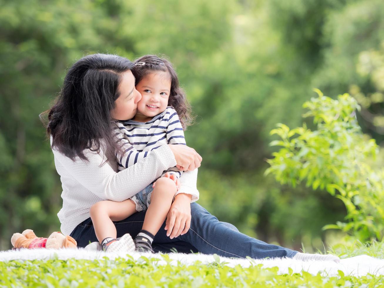 Asian little girl sitting with her mom on the carpet, Relax and learning outside of school to enjoy in the nature park photo