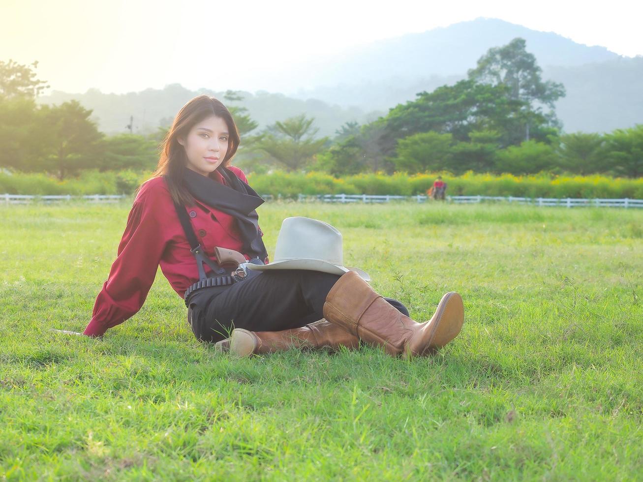 A beautiful western cowgirl sitting on a meadow on a farm after hard work photo