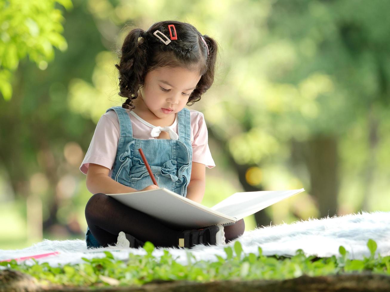 The girl sitting on the carpet, drawing with colored pencils photo